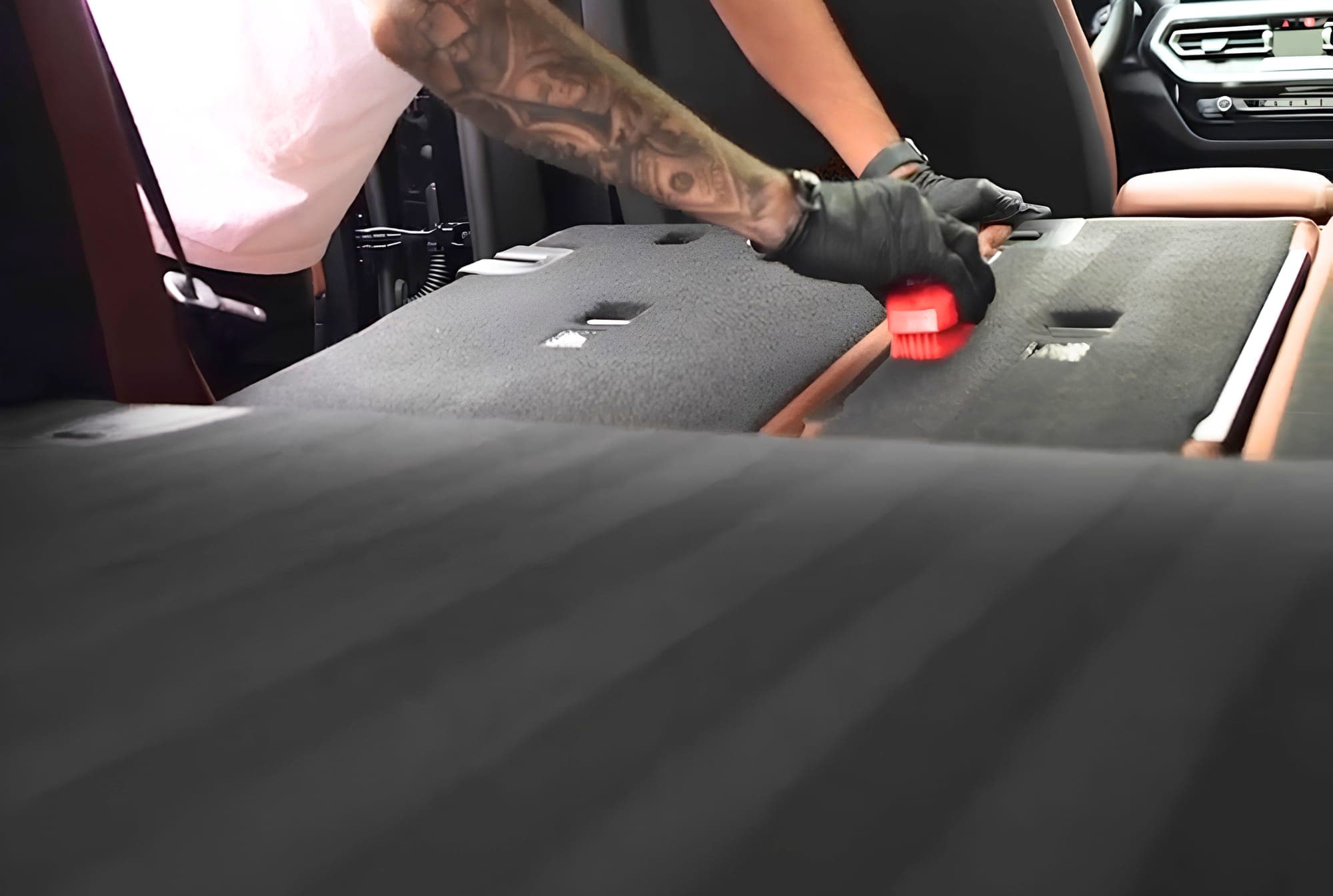 A detailing brush working along a car’s cargo-area carpet