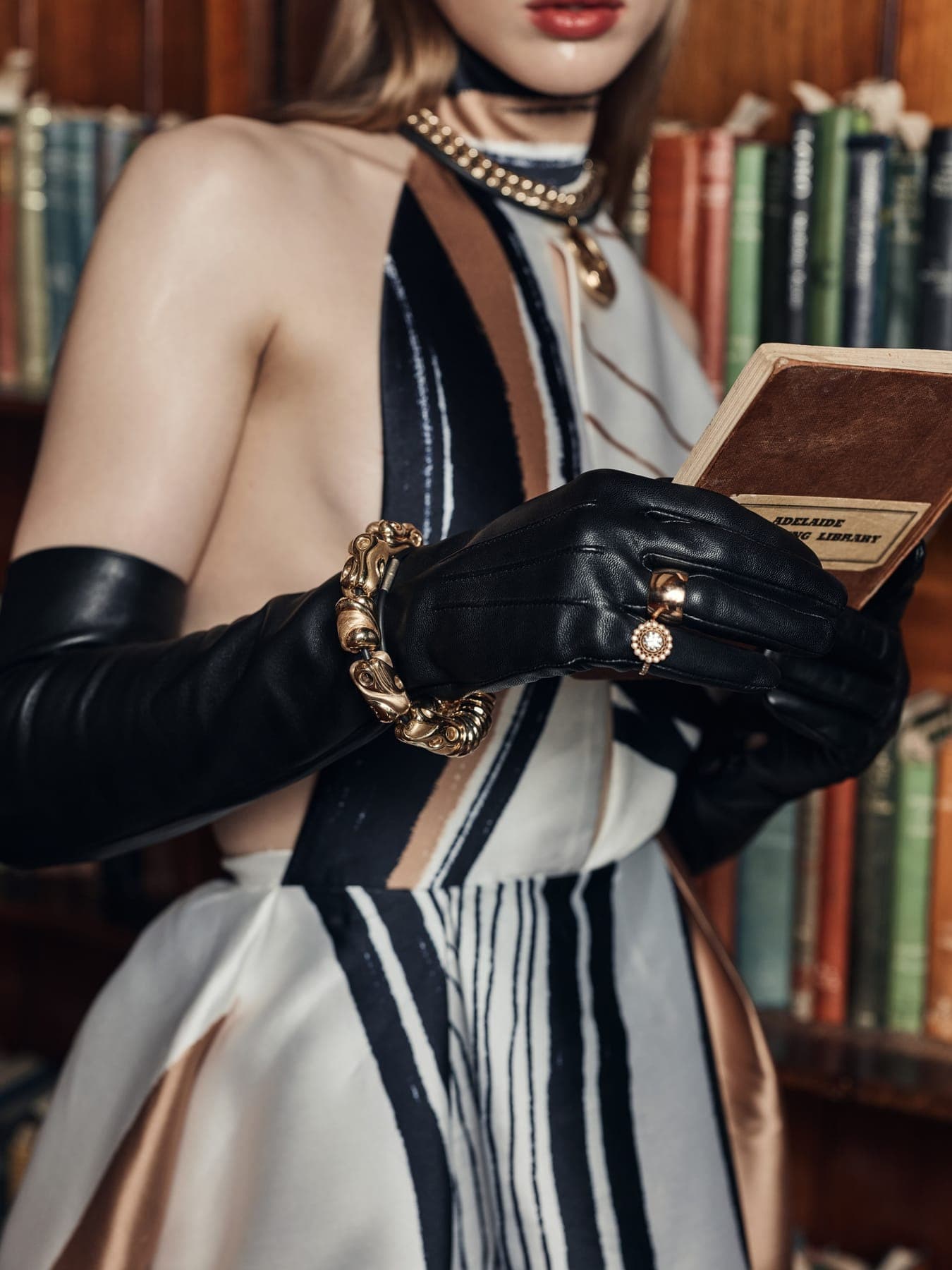 Gloved hands holding a book in front of a bookshelf