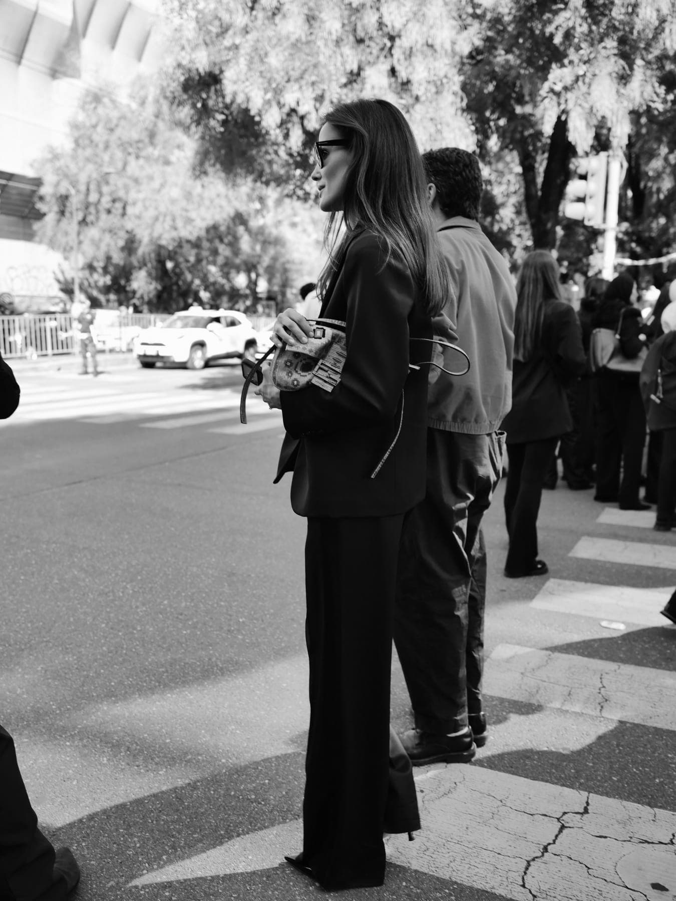 Person in dark tailoring waiting at a street crossing