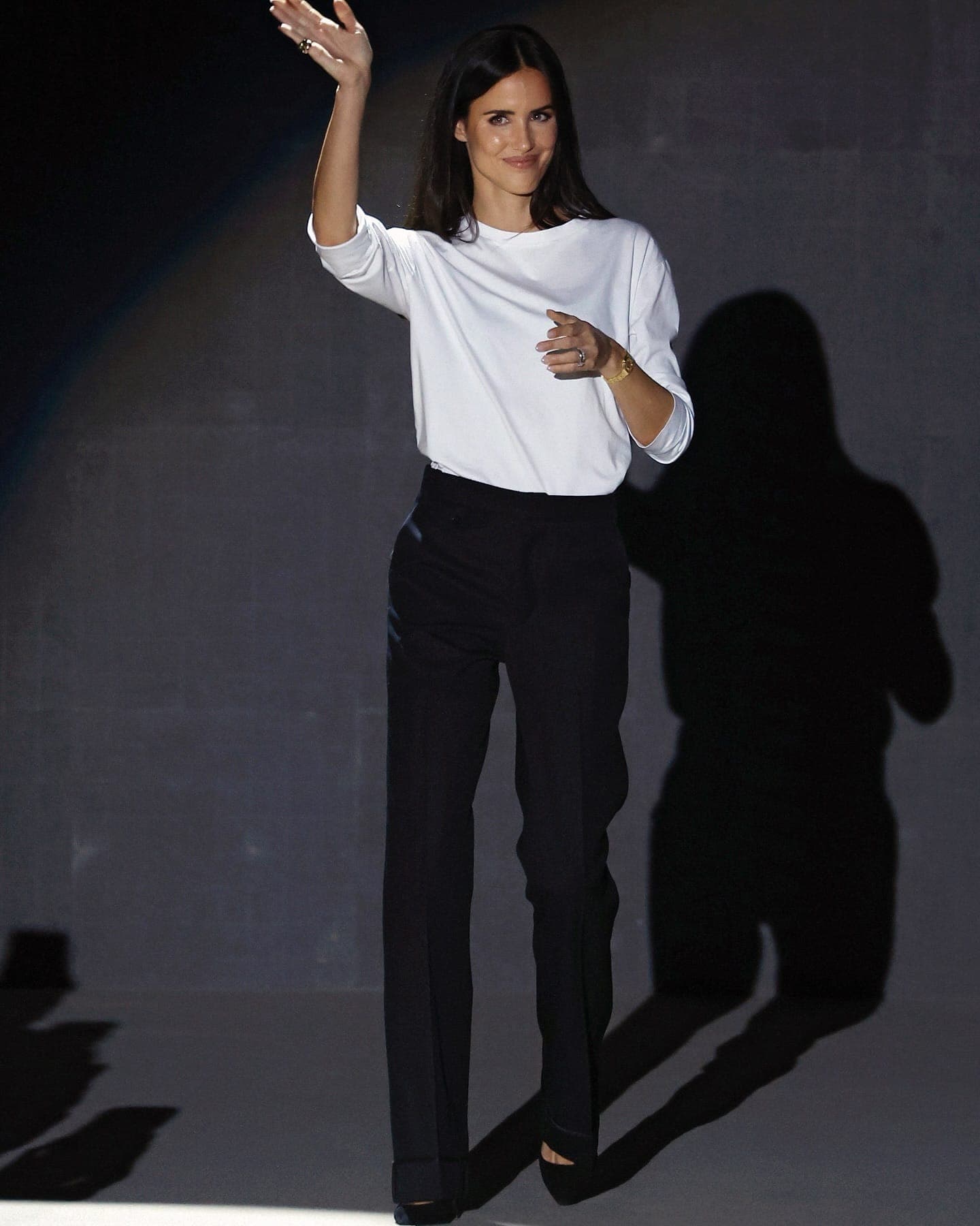 Person in a white T-shirt against a grey wall with a hard shadow
